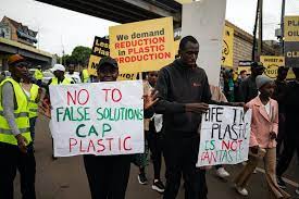 مردم با تابلوهایی راهپیمایی می کنند که خواستار محدودیت در تولید پلاستیک هستند.